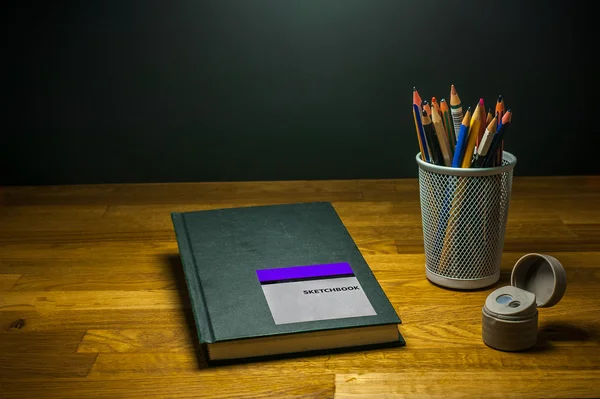 Ξύστρα μολυβιών μολύβια χρώματος και sketchbook για φοιτητές τέχνης στο τραπέζι — Φωτογραφία Αρχείου