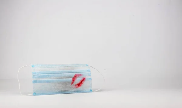 İzole edilmiş yüz maskesi ve beyaz bir arka planda ruj izi. Salgın sırasında aşk için bir metafor. Sevgililer Günü için mükemmel..