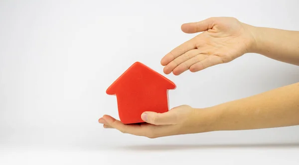 Bir elinde kırmızı ev heykelciği, diğer elinde ise dürüst bir gayrimenkul satışı ya da alımını temsil eden bir heykel.