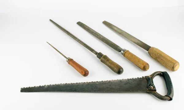 Klasik ahşap işçiliği dosyaları ve beyaz arka planda düz duran testere. Ağır kullanılmış dört tahta dosya ve eski bir el testeresi var..