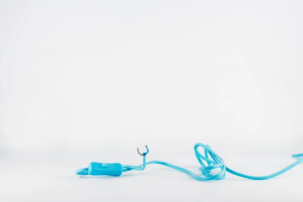 Beyaz zemin üzerinde plastik şalter olan uzun mavi karmaşık elektrik kablosu. Kablo kesilmiş ve iki korumasız kabloyu gösteriyor..