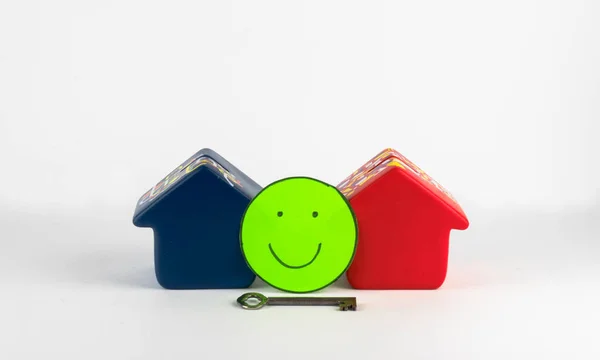 İki ev, anahtar ve yeşil gülen bir yüz iyi bir emlak piyasasını temsil ediyor. Mutlu yüz, potansiyel alıcıları piyasayı keşfetmeye ve ilk evlerini satın almaya teşvik eder..