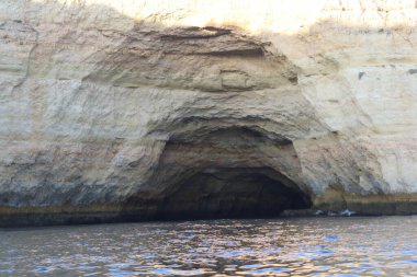 Güney Portekiz 'deki Algarve sahili boyunca kireçtaşı kayalıklara oyulmuş doğal deniz mağarası girişi. Engebeli kaya oluşumları ve derin gölgeler Atlantik Okyanusu 'nun turkuaz sularıyla çok güzel tezat oluşturuyor. Çarpıcı bir kıyı manzarası.