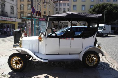 Lizbon, Portekiz 'de turistik turlarda kullanılan klasik bir arabaya benzemesi için tasarlanmış beyaz elektrikli bir tuk-tuk' un editoryal fotoğrafı. Araç Rossio Meydanı 'nın yakınındaki geleneksel taş kaldırımda park halinde.
