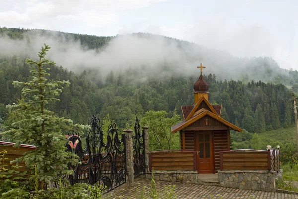 Chapel in the mountains on the background of wooded hillsides — Stock Photo, Image