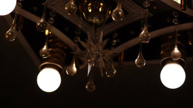 Kırmızı ampulleri ve kristal damlacıkları olan bir avize ve yakın plan siyah arkaplanda bir yıldız işareti.       