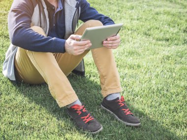 Dijital Tablet parkta çimlere oturup kadar alay kullanan adam