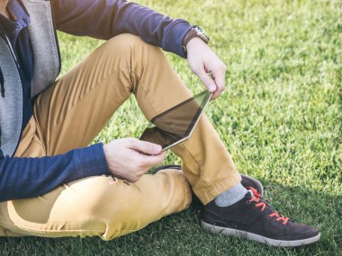 Dijital Tablet parkta çimlere oturup kadar alay kullanan adam