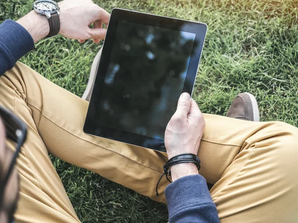 Mann mit digitaler Tablet-Attrappe mit leerem Bildschirm sitzt auf dem Gras im Park — Stockfoto