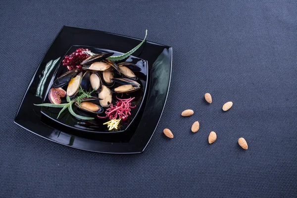 Mejillones en plato negro con nueces. Almendras —  Fotos de Stock
