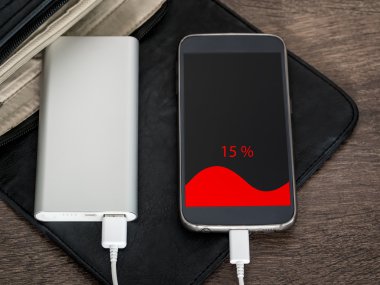 Smartphone charging with power bank. 15 percent of charge