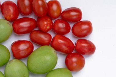 Beyaz arka plana karşı taze yeşil ve kırmızı domates yığını. Beyaz arka planda izole edilmiş yeşil ve kırmızı domates grubu. Kapat.