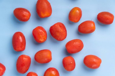 Mavi arka planda izole edilmiş bir grup kiraz domatesi. Taze vişneli domates yığını mavi arka planda izole edilmiş..