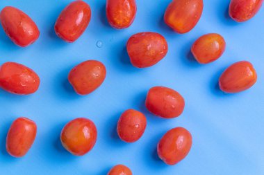 Mavi arka planda izole edilmiş bir grup kiraz domatesi. Taze vişneli domates yığını mavi arka planda izole edilmiş..