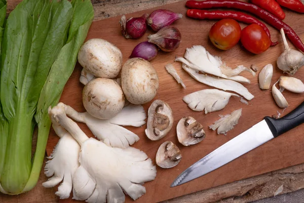 ready to cook. mushrooms, chilies, garlic and shallots on a wooden cutting board