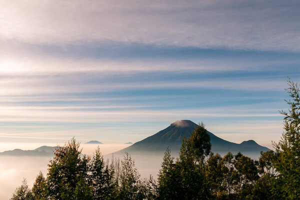 View of the sindoro mountains with a sea of clouds in central java Indonesia from the top early in the morning