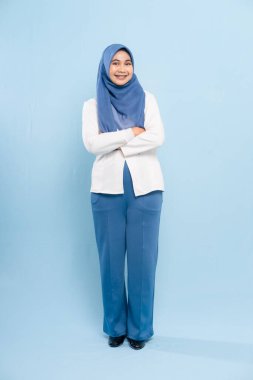 Profesyonel, mütevazi iş kıyafetleri giymiş genç bir Asyalı Müslüman kadının tam boy stüdyo fotoğrafı..