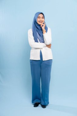Profesyonel, mütevazi iş kıyafetleri giymiş genç bir Asyalı Müslüman kadının tam boy stüdyo fotoğrafı..