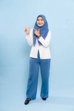 Mavi tesettürlü ve iş kıyafeti giyen genç bir Asyalı Müslüman önemli bir tavsiyeye işaret ediyor..