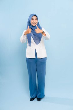 Mavi tesettürlü ve iş kıyafeti giyen genç bir Asyalı Müslüman iki eliyle birden 