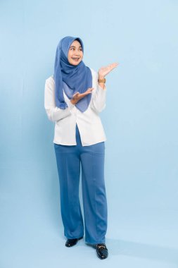 Mavi tesettürlü ve iş kıyafeti giyen genç bir Asyalı Müslüman önemli bir tavsiyeye işaret ediyor..