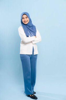 Profesyonel, mütevazi iş kıyafetleri giymiş genç bir Asyalı Müslüman kadının tam boy stüdyo fotoğrafı..