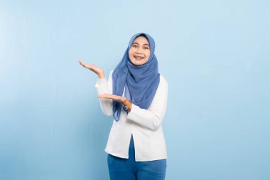 Mavi tesettürlü ve iş kıyafeti giyen genç bir Asyalı Müslüman önemli bir tavsiyeye işaret ediyor..