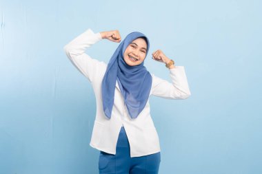 Yarı gövdeli bir stüdyo, neşeli bir Asyalı Müslüman 'ı kollarını esneterek güç, kendine güven veya kişisel ve profesyonel kilometre taşlarını kutlarken çekiyor..