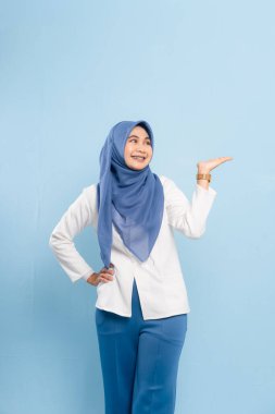 Mavi tesettürlü ve iş kıyafeti giyen genç bir Asyalı Müslüman önemli bir tavsiyeye işaret ediyor..