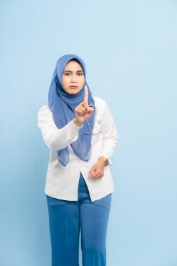 Ciddi bir Asyalı Müslüman doktor ya da hemşirenin mavi arka planda izole edilmiş parmaklarıyla 