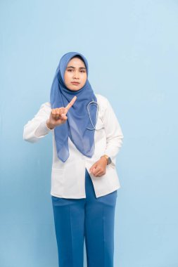 Ciddi bir Asyalı Müslüman doktor ya da hemşirenin mavi arka planda izole edilmiş parmaklarıyla 