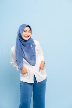 Kendinden emin ve gülümseyen Asyalı Müslüman bir doktorun ya da steteskoplu bir hemşirenin portresi..