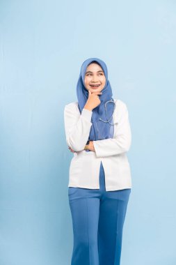 Endişeli bir Asyalı Müslüman doktorun ya da hemşirenin portresi derin düşünen, mavi bir arka plan izole etti..