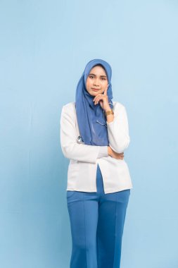 Endişeli bir Asyalı Müslüman doktorun ya da hemşirenin portresi derin düşünen, mavi bir arka plan izole etti..