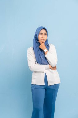 Endişeli bir Asyalı Müslüman doktorun ya da hemşirenin portresi derin düşünen, mavi bir arka plan izole etti..