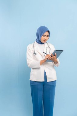 Gülümseyen Asyalı Müslüman Doktor veya Dijital Tablet üzerinde çalışan Hemşire. Mavi arkaplanda izole edilmiş