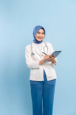 Gülümseyen Asyalı Müslüman Doktor veya Dijital Tablet üzerinde çalışan Hemşire. Mavi arkaplanda izole edilmiş