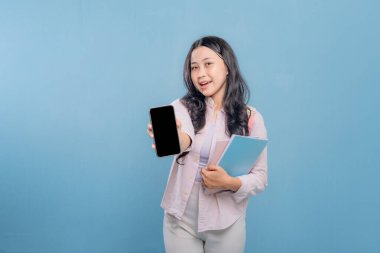 Bir kadın elinde cep telefonu ve bir yığın kitap tutuyor. Kadın cep telefonundan bilgileri göstermek istiyor.