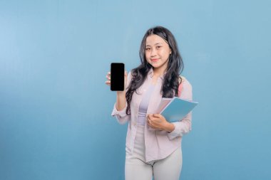 Bir kadın elinde cep telefonu ve bir yığın kitap tutuyor. Kadın cep telefonundan bilgileri göstermek istiyor.