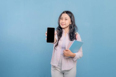 Bir kadın elinde cep telefonu ve bir yığın kitap tutuyor. Kadın cep telefonundan bilgileri göstermek istiyor.