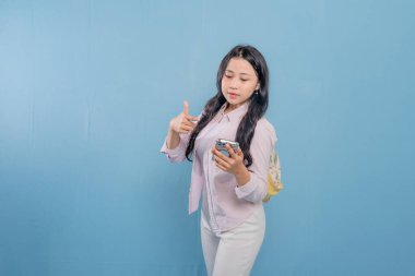 Bir kadın elinde cep telefonu ve bir yığın kitap tutuyor. Gülümsüyor ve mutlu.