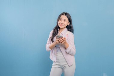 Elinde cep telefonu olan bir kadın fotoğraf için poz veriyor. Modern teknoloji ve iletişim kavramı