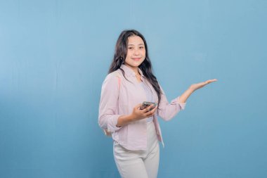 Bir kadın cep telefonunu tutar ve önemli bir şeye işaret eder. Gülümsüyor ve mutlu. Modern teknoloji ve iletişim kavramı