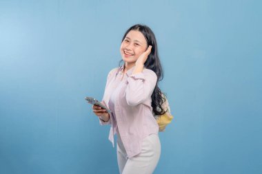 Bir kadın elinde cep telefonu olan bir resme poz veriyor. Modern teknoloji ve iletişim kavramı