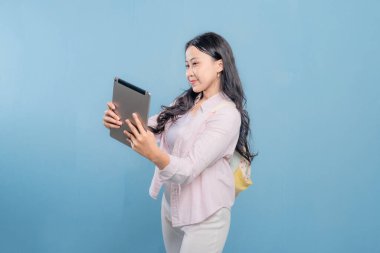 Genç bir kadın elinde bir tablet tutuyor ve gökyüzünü işaret ediyor. Gülümsüyor ve bir şey hakkında heyecanlı ya da meraklı.