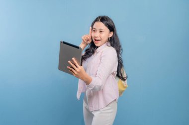 Genç bir kadın elinde bir tablet tutuyor ve gökyüzünü işaret ediyor. Gülümsüyor ve bir şey hakkında heyecanlı ya da meraklı.