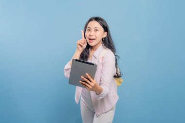 Genç bir kadın elinde bir tablet tutuyor ve gökyüzünü işaret ediyor. Gülümsüyor ve bir şey hakkında heyecanlı ya da meraklı.