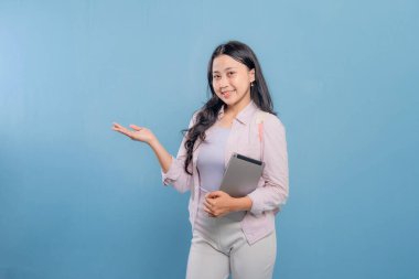 Bir kadın elinde bir tablet tutuyor ve onu işaret ediyor. Gülümsüyor ve mutlu.