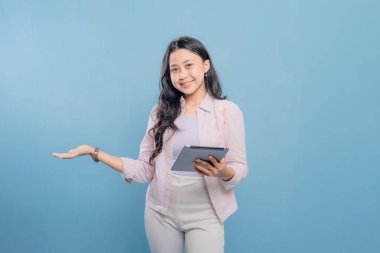 Bir kadın elinde bir tablet tutuyor ve onu işaret ediyor. Gülümsüyor ve mutlu.