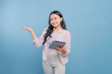 Bir kadın elinde bir tablet tutuyor ve onu işaret ediyor. Gülümsüyor ve mutlu.